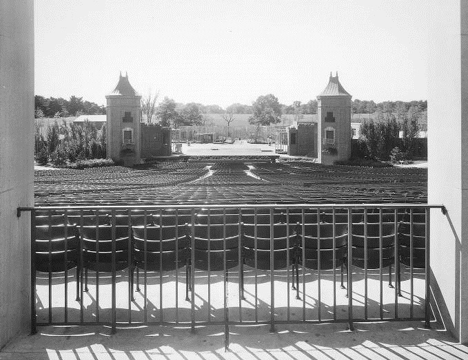 Black and white photo from back of audience looking at original stage without a cover