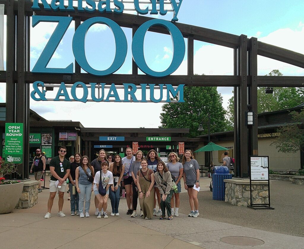 The group of interns in front of the Kansas City Zoo sign