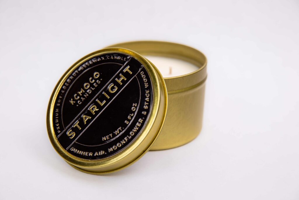 A gold candle with a black lid that says Starlight. The scent is summer air, moonflower, and stage wood.
