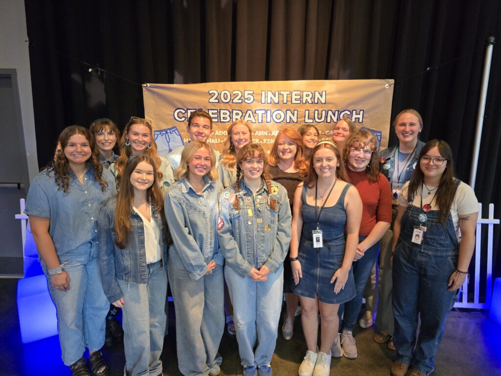 The group of interns standing with Starlight's CEO in front of the Jean Party decorations.