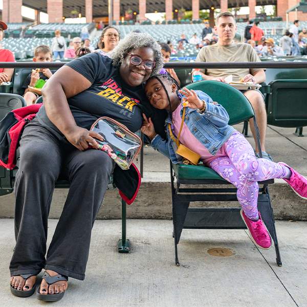 A woman and a young girl sitting in Starlight's green seats, smiling at the camera.