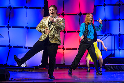 Three students dance and sing on stage during the Blue Star Awards Ceremony.