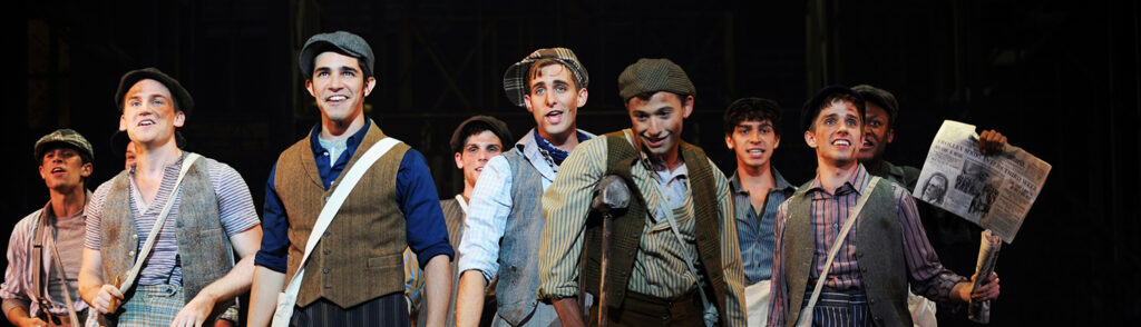 A group of men dressed in old time clothing during a production of Newsies.