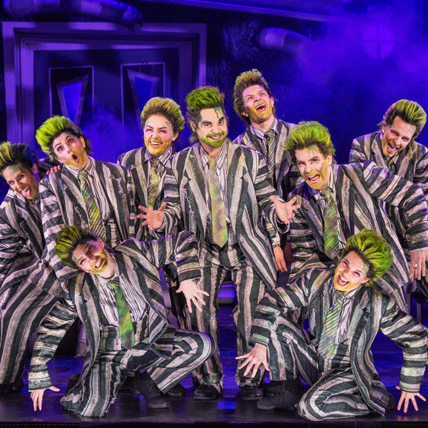 A group of Beetlejuice characters dance and sing on stage.