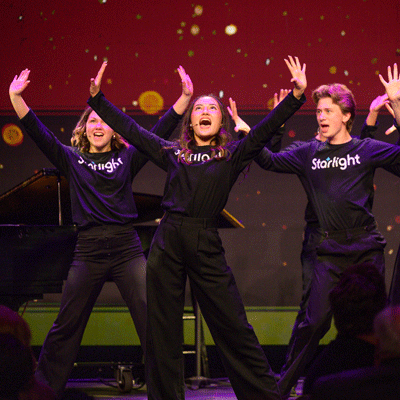 Students dressed in black shirts sing with their arms raised at Starlight's Gala.