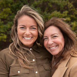 A white woman with brown hair and blonde highlights wearing a brown shirt and a white woman with brown hair wearing a brown jacket