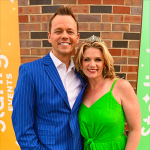 White man wearing a bright blue suite with white stripes and a white woman with blond hair wearing a green dress