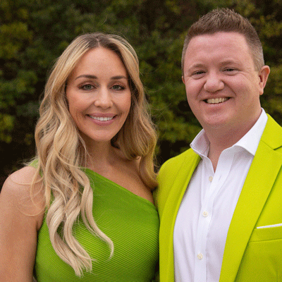 White woman with long blonde hair wearing a green dress and a white male wearing a white button down shirt with a lime green blazer