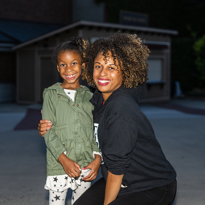 A young girl standing by a woman with her arm around her