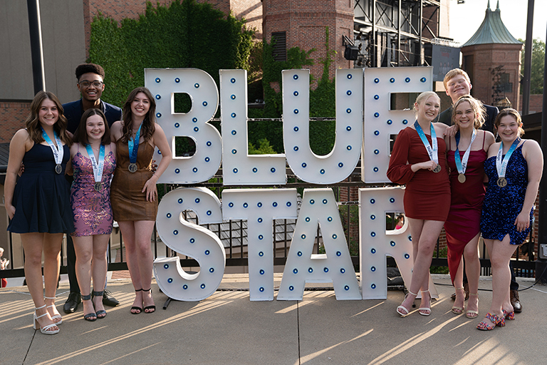 A group of students standing by a photo op that says Blue Star