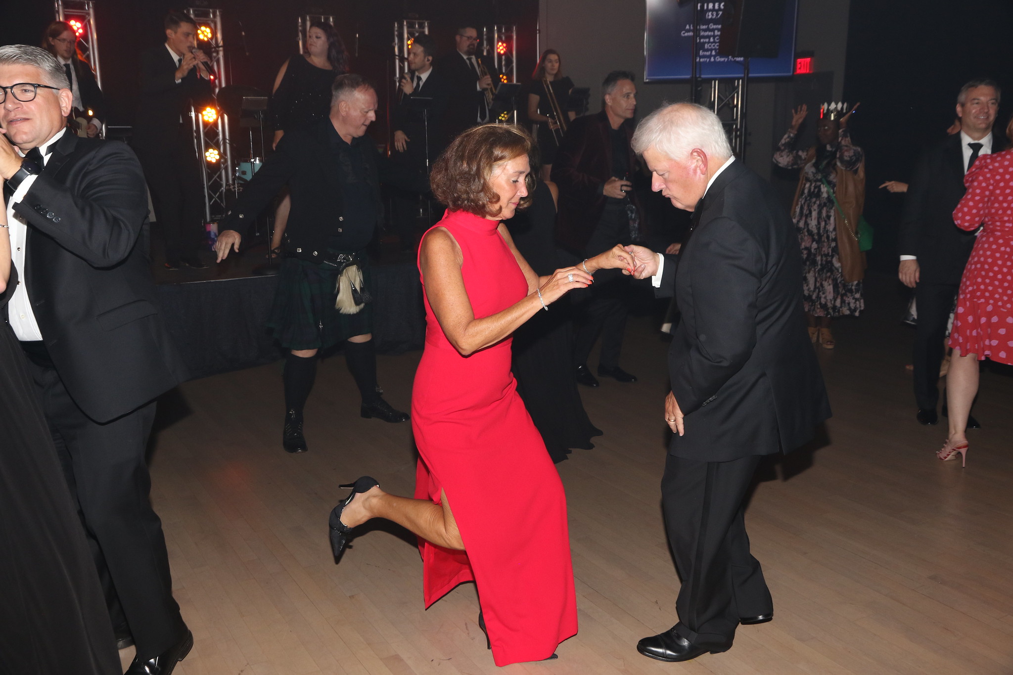 A woman in a red dress dancing lively with a man in a dark suit