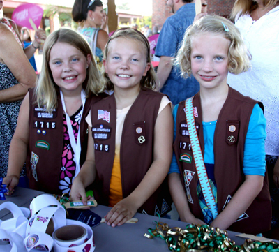 Three girls in Brownies vests smiling at the camera