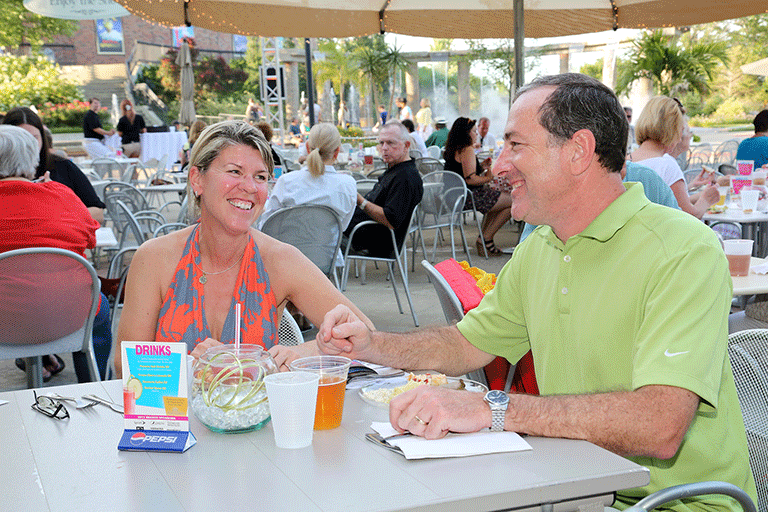 A couple sitting outside eating and drinking on the Starlight patio