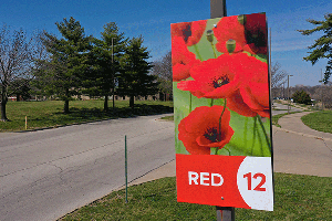 A sign with Red 12 and red poppies hanging on a pole at the entrance of Starlight.