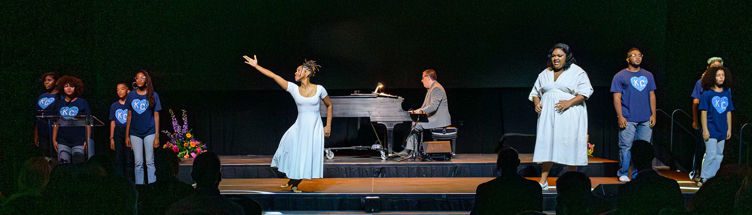 Performers on stage singing with a dancer